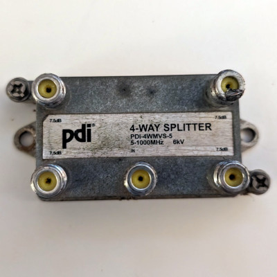 An aged and weathered coaxial splitter with one input and four outputs, labeled as supporting up to 1000Mhz
